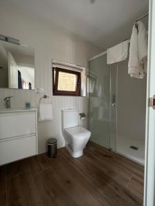 a white bathroom with a toilet and a shower at Finca El Palomar de Luanco in Luanco