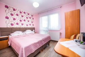 Dormitorio rosa con cama y mesa en Dom Wczasowy Grażyna, en Władysławowo