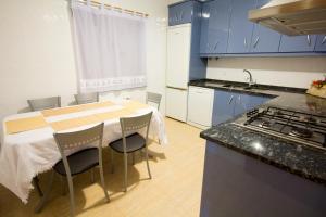 una cucina con armadi blu e tavolo con sedie di Casa Rural Escapada Rústica Teruel a Teruel