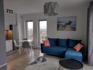 uma sala de estar com um sofá azul e uma mesa em Apartament Rumia Trójmiasto Kaszuby em Rumia