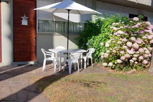 una mesa y sillas con sombrilla y flores en Apartamento con entrada independiente y jardín, en Punta del Este