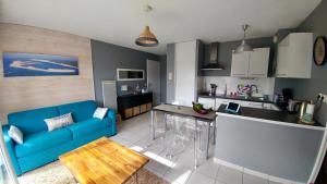 a living room with a blue couch and a kitchen at Joli Appartement Audenge in Audenge