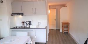 una cucina con armadi bianchi e un tavolo in una stanza di Résidence Cap Azur Appartement 209 a Villeneuve-Loubet