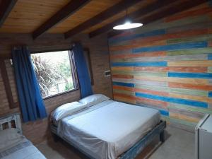 Dormitorio con pared colorida, cama y ventana en EL ZORZAL Dormis con Galeria en Villa del Dique
