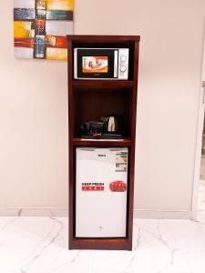 a small refrigerator in a shelf with a microwave at Qaser Sadan in Ad Dawādimī