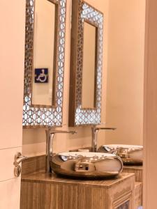 a bathroom with two sinks and two mirrors at Qaser Sadan in Ad Dawādimī
