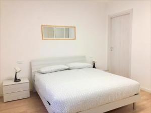 una camera bianca con un letto e una foto appesa al muro di Casa Gege Pavia Città a Pavia