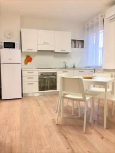 una cucina con armadi bianchi, tavolo e sedie di Casa Gege Pavia Città a Pavia