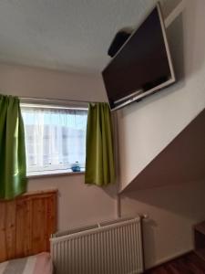 a bedroom with green curtains and a television on the wall at Ferienwohnung Stockenhuber in Sankt Martin am Grimming