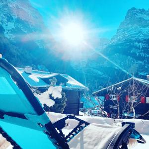 een uitzicht op een met sneeuw bedekte berg met de zon bij Chalet Pfingsteggblick in Grindelwald