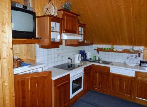 a kitchen with wooden cabinets and a tv on the wall at Kleines Ferienhaus Koglerhütte in Rossleithen