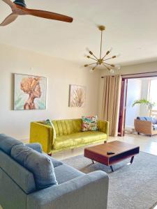 a living room with a yellow couch and a table at La Mera Ocean-View, 2 Bedroom - Apartment with Pool and NEW renovated Art Style Rooms in Shanzu