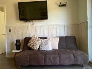 un sofá marrón en la sala de estar con TV de pantalla plana en Bello y acogedor departamento en Pucón, en Pucón