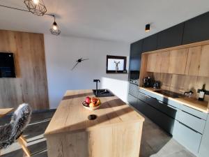 a kitchen with a bowl of fruit on a wooden island at Apartmán Pod Hochfichtem in Nová Pec