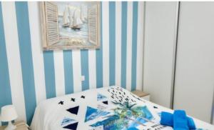 1 dormitorio con 1 cama con rayas azules y blancas en Nueva Europa apartamentos, en Maspalomas