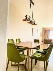 a dining room with a wooden table and green chairs at La Mera Ocean-View, 2 Bedroom - Apartment with Pool and NEW renovated Art Style Rooms in Shanzu