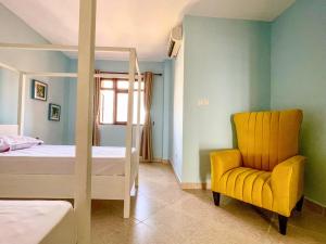 a bedroom with a bed and a yellow chair at La Mera Ocean-View, 2 Bedroom - Apartment with Pool and NEW renovated Art Style Rooms in Shanzu