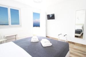 a white bedroom with a bed with two towels on it at Crystal View Mykonos in Mikonos