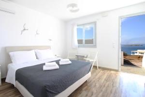 a white bedroom with a bed and a view of the ocean at Crystal View Mykonos in Mikonos