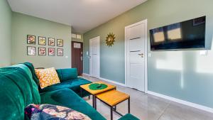希维拉杜夫-兹德鲁伊Apartament Kwiatowy - 5D Apartamenty的客厅里有一张绿色的沙发和一张桌子