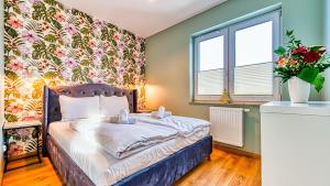 希维拉杜夫-兹德鲁伊Apartament Kwiatowy - 5D Apartamenty的卧室里有一张床，墙上挂着花