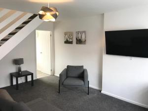 a living room with a chair and a flat screen tv at Property Hunter 23 in Darlington