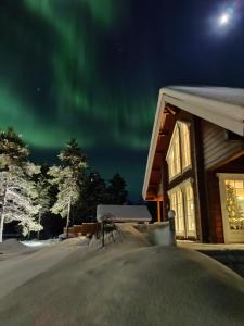 una cabaña con la aurora en el cielo por la noche en Villa Huilinki, en Ranua