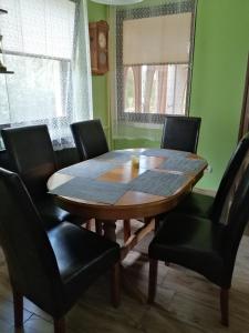 uma mesa de jantar com cadeiras pretas e uma mesa de madeira em GOLDENVENDÉGHÁZ em Balatonszabadi