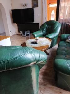 uma sala de estar com dois sofás de couro verde e uma mesa em GOLDENVENDÉGHÁZ em Balatonszabadi