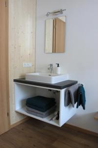 y baño con lavabo blanco y espejo. en Bergreich Appartement 3, en Schoppernau