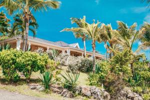 een huis met palmbomen ervoor bij Hotel La Plantation in Orient Bay