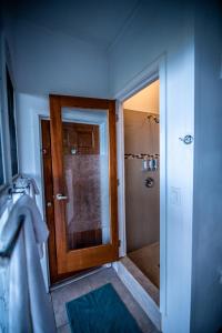 a bathroom with a shower with a wooden door at Papaya Suite at Sunset Serenade in Enighed