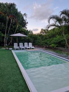 a swimming pool with two chairs and an umbrella at Bossa Beach House in Ilha do Mel
