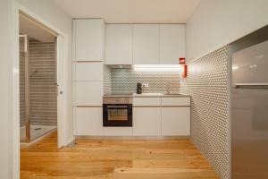 La cuisine est équipée de placards blancs et d'un four avec plaques de cuisson. dans l'établissement River Eyes Apartments, à Porto