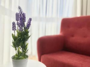 un jarrón con flores púrpuras en una mesa junto a una silla roja en Sofía Suites, en Cambrils