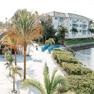 a resort with a pool and palm trees and a building at The Suites at Fishermen's Village - 2 Bedroom Suites in Punta Gorda
