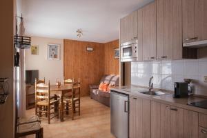 - une cuisine avec des placards en bois, une table et un canapé dans l'établissement El Rincón de Andrea Apartamentos, à Biescas
