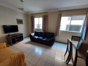 ein Wohnzimmer mit einem Sofa und einem TV in der Unterkunft Lindo apartamento 50 metros da praia do morro, três quartos e duas vagas de garagem in Guarapari