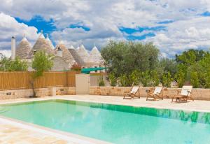 a swimming pool with chairs and a house at Il Calàscione Apulian Villas in Locorotondo