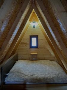 a bed in a wooden room with a window at BB CHALET in Kolašin