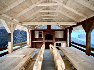 a large wooden pavilion with benches and a fireplace at BB CHALET in Kolašin