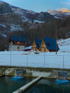 une maison dans la neige à côté d'une rivière dans l'établissement BB CHALET, à Kolašin