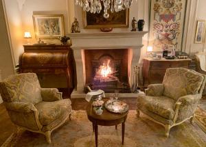 ein Wohnzimmer mit einem Kamin, 2 Stühlen und einem Tisch in der Unterkunft Château Ratou in Saint-Lys