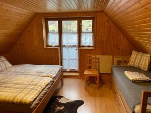 een zolderkamer met twee bedden en een raam bij Chalupa Čičmany in Čičmany