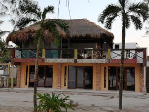 un edificio con techo de paja y dos palmeras en Xcalak Caribe Lodge, en Xcalak