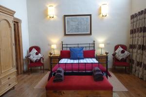 a bedroom with a bed with two red chairs at Shed End, in 18th century Lothersdale Mill BD20 8EN in Lothersdale