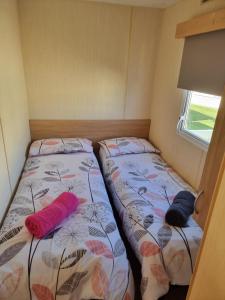 two twin beds in a small room with a window at Meadow Lakes 39 in Skegness