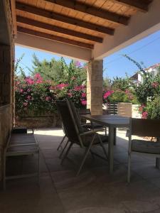 Khlóï的住宿－Πέτρινη κατοικία στην Αίγινα - Stone House in Aigina，庭院配有桌椅和粉红色的鲜花。