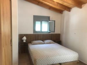 a bedroom with a bed with a mirror and a window at Πέτρινη κατοικία στην Αίγινα - Stone House in Aigina in Khlóï
