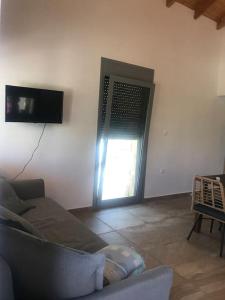 ein Wohnzimmer mit einem Sofa und einer Tür mit einem Fenster in der Unterkunft Πέτρινη κατοικία στην Αίγινα - Stone House in Aigina in Khlóï